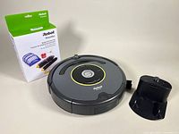 iRobot Roomba 652 vacuum, replenishment kit box, and docking station displayed on neutral background.
