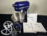 Overview of cobalt blue mixer, stainless bowl, splash guard, attachments and boxes