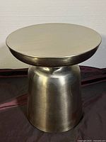 Front angle view of the metal side table showing its cylindrical shape and brushed finish.