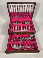 Full view of the open wood chest containing the silver plate cutlery set arranged in two tiers with deep pink felt.