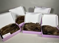 Five Paula Young wigs in original purple and white boxes, styles visible from the top with hair arranged inside the boxes.