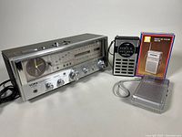 Full view of the three radios: Yorx clock radio with analog clock and tuning dials; Jutan AM-FM radio with black body and silver grill; Sound Design pocket radio with original box and manual.