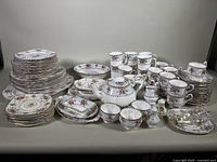 Overall view of stacked plates, cups, teapot, sugar bowl, creamer and serving pieces