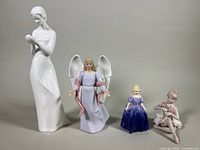 Photo showing six porcelain figurines including Royal Doulton "Tenderness" tall white figurine, HMK LIC angel, and three small child figurines of various colors and sizes.