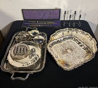 Full overview of all silver plated serveware including trays, creamer, sugar bowl, napkin rings, carving set in case, and candlestick holders