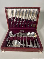 Full view of the open silverware case displaying the knives set vertically on the lid and various spoons and forks in the base compartments.