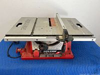 Full view of Skilsaw table saw showing flat working surface with blade slot, metallic table and red base.