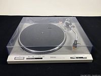 Technics SL-D202 turntable with clear dust cover on, showing full unit from top front angle on black background.
