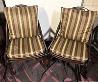 Front view of two wooden chairs with striped fabric cushions and woven seats.