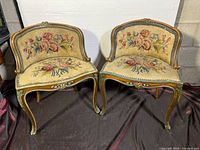 Front view of two Louis XV style music chairs placed side by side showing floral tapestry on seat and backrest with carved wooden frame detail.