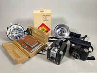 Overview of all items including Polaroid SX-70 box and inserts, Brownie Hawkeye with flash attachment, Rexo camera and zoetrope disc