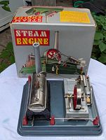 Front view of the original box and the steam engine model with visible details like red flywheel, chimney, and boiler.