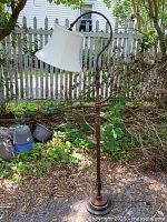 Full view of the vintage 1950s floor bridge lamp showing the brass base, wooden and metal stem, curved arm, and white fabric shade.