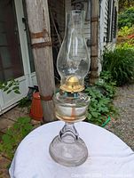 Full view of the entire lamp placed on white cloth showing clear glass construction with star pattern on the base and chimney at top
