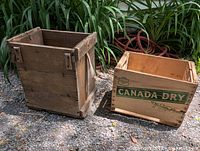 Two antique wooden boxes outdoors. One solid pine wood box, another branded Canada Dry crate.