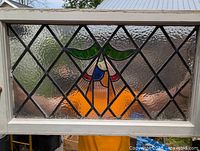 Front view of the antique Victorian stained glass window showing the colored glass floral or abstract design with leaded diamond patterned glass and pine frame.