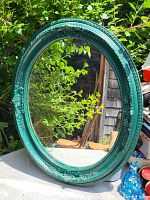 Full view of the teal oval mirror showing overall condition and decorative frame detail.