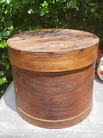 Overall view of early wooden cheese box showing the top and sides. The wood grain and wear marks are visible.