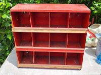 Front view of the red metal hanging parts bin showing three rows with four compartments each.