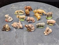 Top view of all 14 animal figurines arranged on a grey surface showing variety of animals and colors.