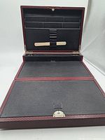 Open burgundy textured portable desk showing ceramic writing surfaces, organizer compartments, and clasp
