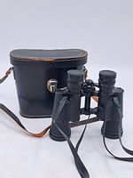 Binoculars standing in front of black hard case showing overall lot