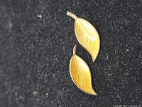 Both yellow enamel leaf earrings on black background