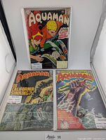 Three Aquaman comic books from the 1960s-70s in protective sleeves, showing vibrant cover art.