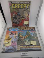 Three Creepy horror comic magazines displayed standing and flat: 1979 Issue #113, 1982 Issue #142, and 1985 Issue #146 Resurrection.