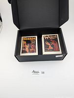 Box showing two sets of collectible cards in black box: Horror Stories and Weird Tales titles visible