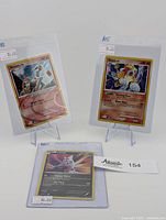 Three Pokemon holographic cards displayed, including 2009 Arceus Cosmo Holo and 2007 Entei Cracked Ice Holo shown upright, 2012 Latias Holo card laying flat.