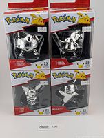Four chrome Pokémon figures in original packaging showing Jigglypuff, Cubone, Eevee, and Pikachu.