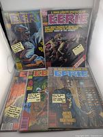 Five Eerie Magazine issues arranged with visible cover art highlighting horror themes and titles, with price tags on top of plastic sleeves.