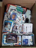 Box filled with assorted baseball cards from various years and sets showing front images of players in various poses.
