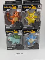 Front view of all four sealed metallic Pokémon figures in original packaging: Charmander, Pikachu, Bulbasaur, and Squirtle.
