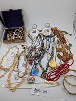 Overview photo showing all jewelry items laid out including necklaces, earrings, bracelets, and a wooden box containing additional pieces.