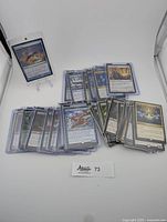 Photo of multiple Magic: The Gathering cards spread out in protective sleeves showing a range of card types and colors.
