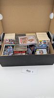 Box filled with large stacks of loose vintage baseball cards from 1980s in various sets.