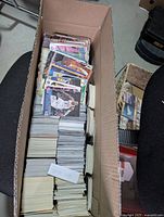 Long view of cardboard box filled with stacked basketball cards