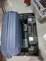 Three tool cases including a blue large case, and two smaller black and green cases in a black crate, showcasing the lot's storage.