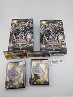 Two sealed Yu-Gi-Oh Dark World Structure Deck boxes and two sealed packs of 30 deck sleeves featuring Dark Magician artwork.