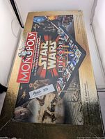 Outer box of Star Wars Episode I Monopoly Collector's Edition game with visible damage, showing the game logo and artwork.