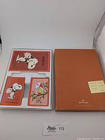 Open box showing two decks of Snoopy playing cards and the orange Hallmark box