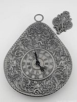 Front view of vintage Berendsohn pewter wall clock showing detailed embossed designs and clock face.