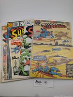 Four vintage Superman comics stacked with visible colorful covers and classic DC Comics branding.