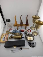 Photo showing entire lot including brass goblets, wooden bottle stoppers, mini flask, EP silver dish, brass bottle opener, red truck bottle opener, unicorn shoe horn, mini flute, and other small brass barware items.