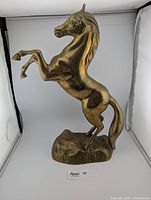 Side view of the vintage brass horse sculpture showing the rearing position and muscular detailing.