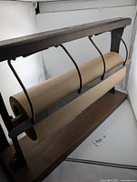 Photo showing the full paper roll cutter with butcher paper roll mounted, illustrating the wooden frame and metal supports.