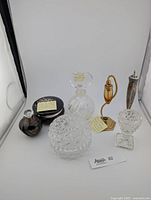 Photo showing all items: alabaster trinket box with gold floral inlay, small brown perfume bottle, lead crystal decanter, vintage perfume atomizer, silver plated salt shaker, crystal trinket dish and egg cup.