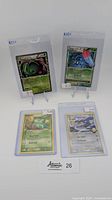 Four Pokemon cards displayed on stands and in plastic sleeves: Meganium holo, Tangrowth holo, Bulbasaur non-holo, Garchomp C non-holo.